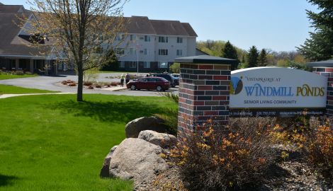 Bright, inviting exterior of Vista Prairie at Windmill Ponds senior living facility in Sheldon, Iowa, featuring landscaped grounds and a prominent sign.