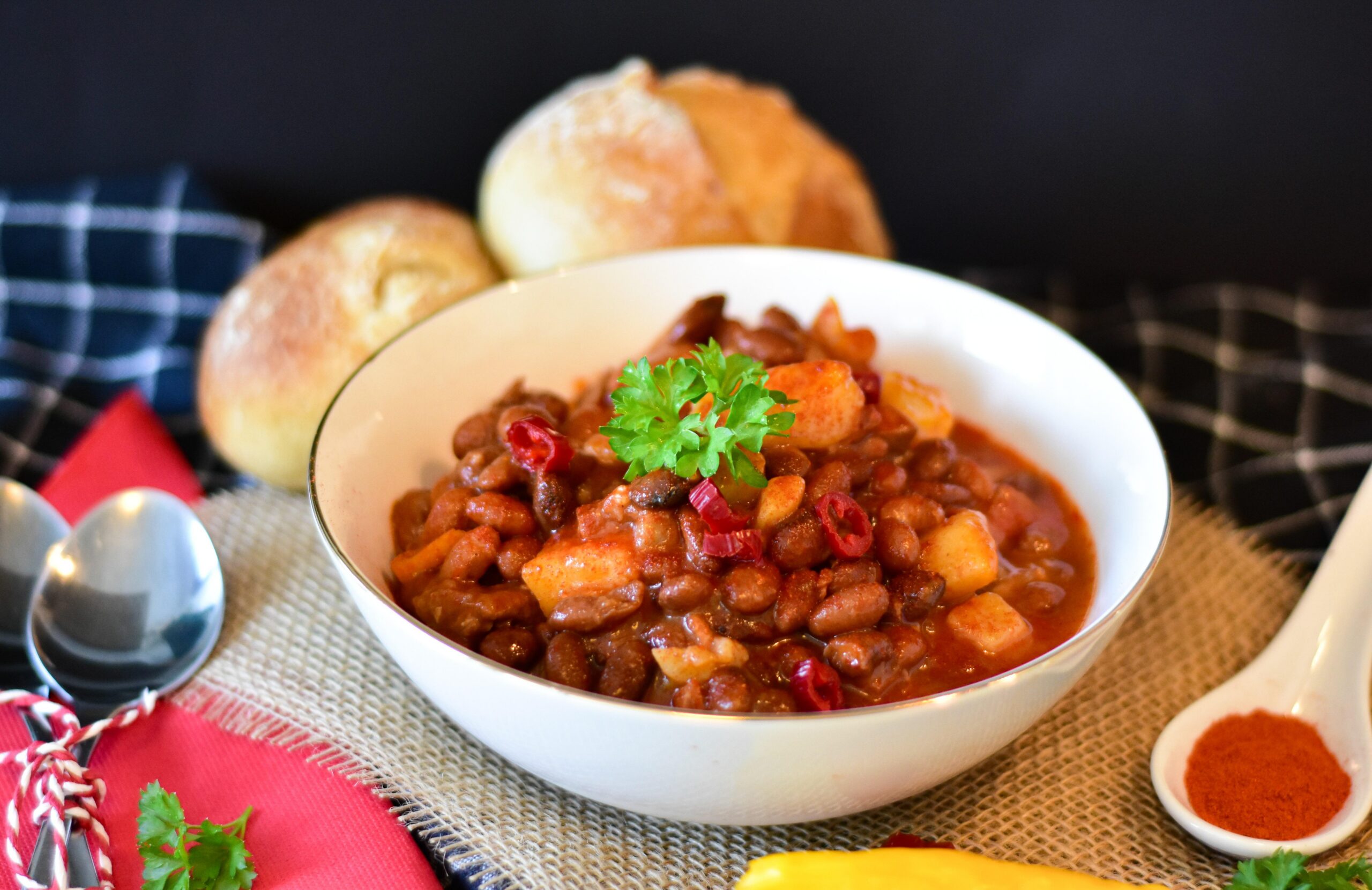 picture of a bowl of chili next to spoons and bread