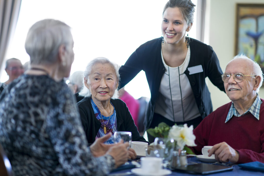 Friendly senior residents enjoying a social gathering at Vista Prairie at Windmill Ponds senior living community in Alexandria, Minnesota, with attentive staff providing personalized care.