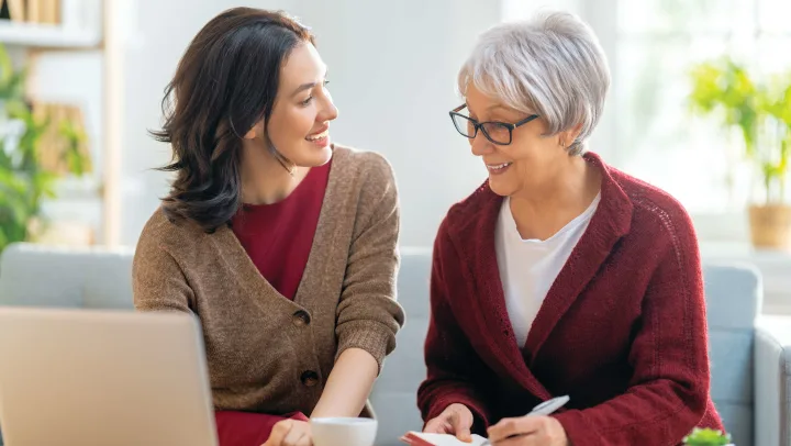 Senior woman and younger woman enjoying conversation at Vista Prairie at Windmill Ponds senior living community in Alexandria, MN, promoting comfortable, engaging retirement lifestyle.