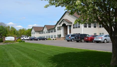 Bright, welcoming exterior of Vista Prairie at Windmi in Alexandria, MN, featuring comfortable senior living apartments, ample parking, and lush green landscaping.