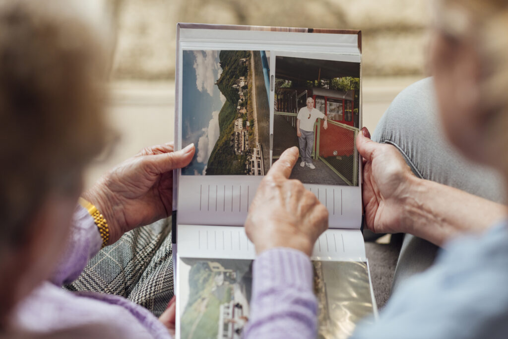 Vintage photo album with scenic images and a person standing on a colorful train at Vista Prairie at Goldfinch Estates senior living community in Fairmont, Minnesota.