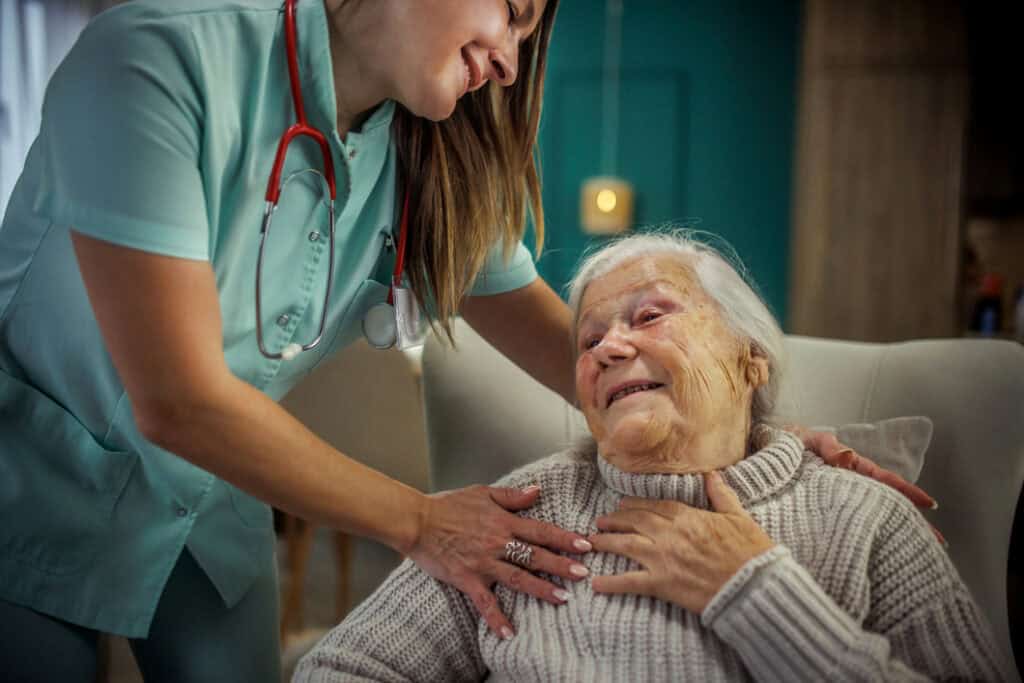 A caring nurse gently interacts with an elderly woman in a cozy senior living environment, showcasing compassionate healthcare services tailored for seniors.
