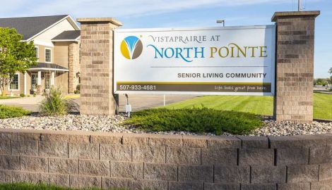 A welcoming senior living community sign at Vista Prairie North Pointe in New Ulm Ridgeway, showcasing a well-maintained outdoor area and community entrance.
