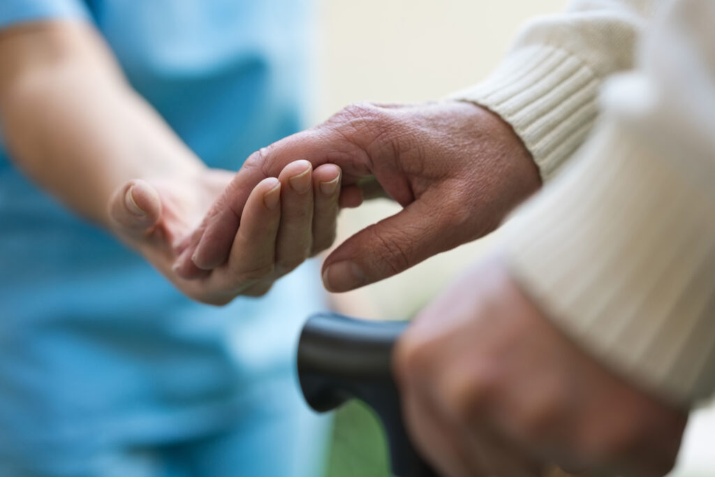 Gentle elderly hand grasping caregiver's hand, symbolizing support and compassionate senior care at Vista Prairie North Pointe senior living in North Mankato, Minnesota.