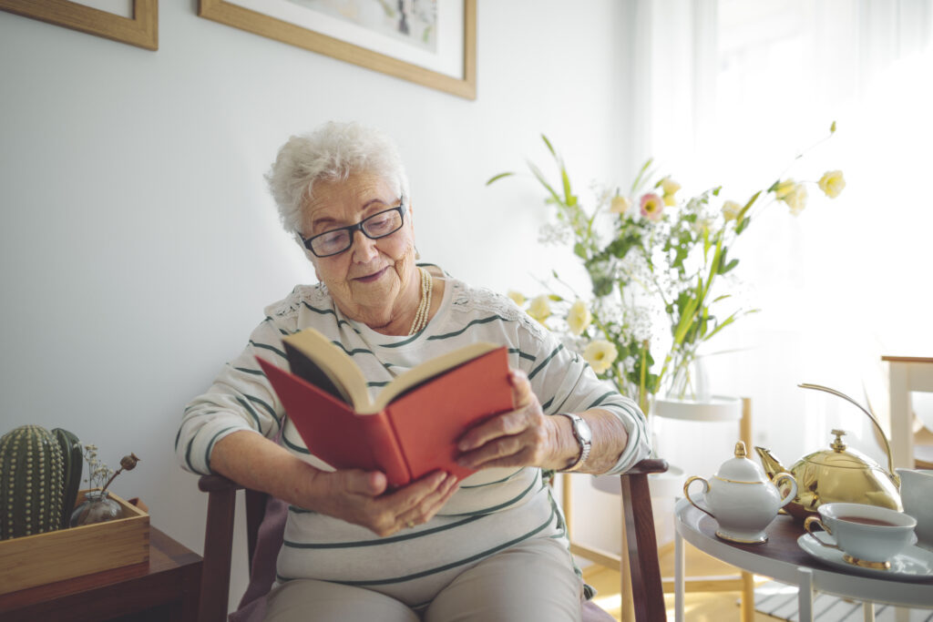 Senior woman reading a book at Vista Prairie at North Pointe senior living community in North Mankato, MN, enjoying a peaceful moment indoors.