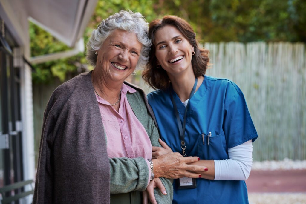 Comfortable elderly woman with senior caregiver smiling outside at Vista Prairie Garnette Gardens senior living community in Redwood Falls MN.