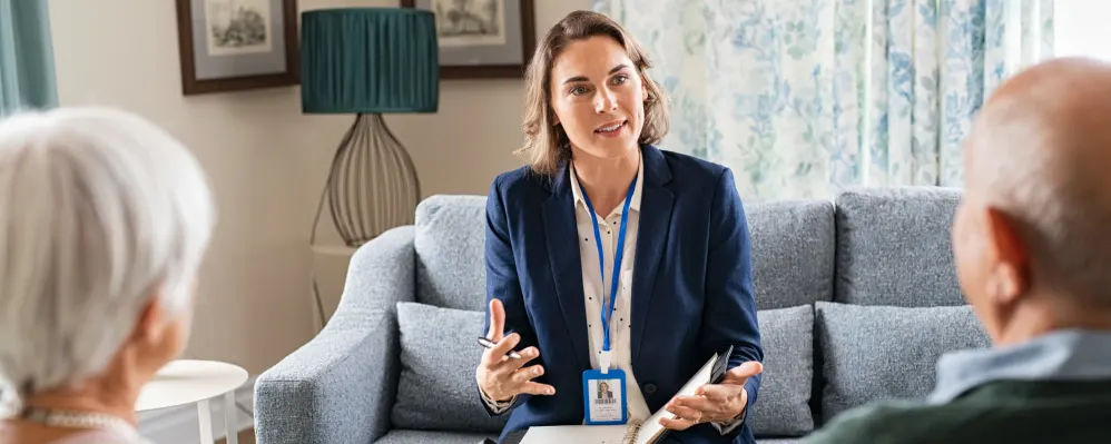 Compassionate senior care advisor discussing options with elderly couple at Vista Prairie at Garnette Gardens nursing home in Redwood Falls, MN.