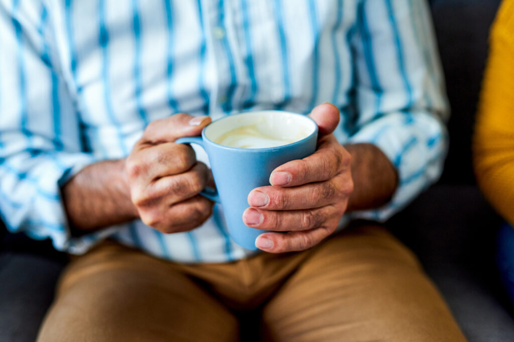 Comfortable senior person holding a blue mug with warm beverage, enjoying a relaxing moment at Vista Prairie at Eagle Pointe senior living community in MN.