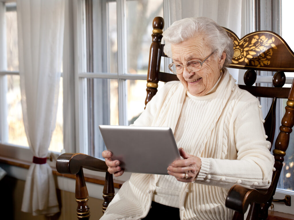 Comfortable elderly woman using a tablet in a cozy senior living environment at Vista Prairie at Eagle Pointe, highlighting senior care and assisted living services in St. Francis, MN.