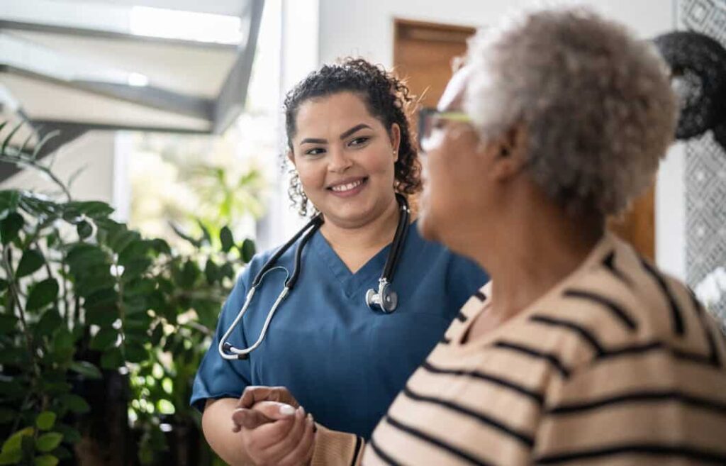 Compassionate healthcare professional engaging with an elderly resident at Vista Prairie at Eagle Pointe senior living community in St. Francis, MN.