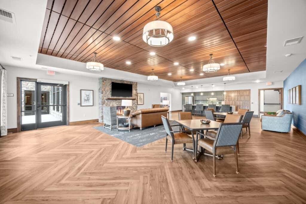 Spacious senior living lounge with modern furniture, wooden ceiling, and ample natural light, providing a welcoming environment for residents.