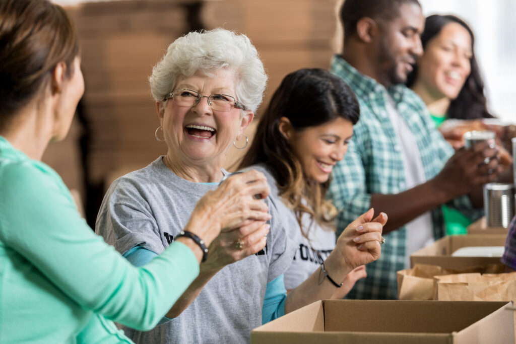 Senior women and diverse adults volunteering at Vista Prairie senior living community in Willmar, MN, packing food donations in a friendly, community-focused environment.