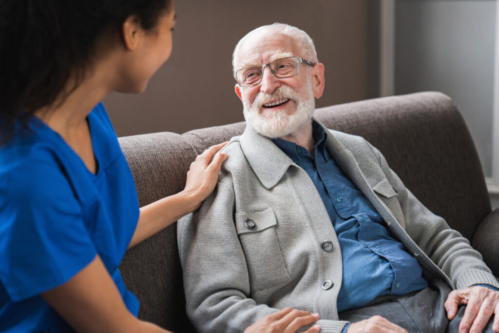 Senior man smiling with caregiver in a senior living community, caring and comfortable environment at Vista Prairie at Copperleaf.