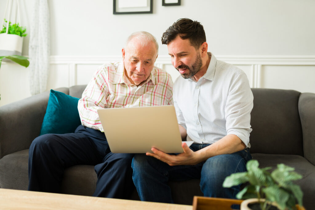 senior man looking at laptop with adult son