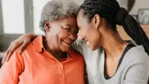 Warm elderly woman and younger caregiver sharing a heartfelt moment at Vista Prairie Communities senior living facility.