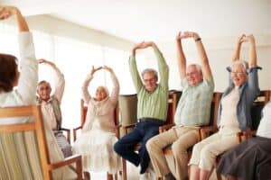 Senior residents engaging in seated stretching exercises during a recreational activity at Vista Prairie Communities.